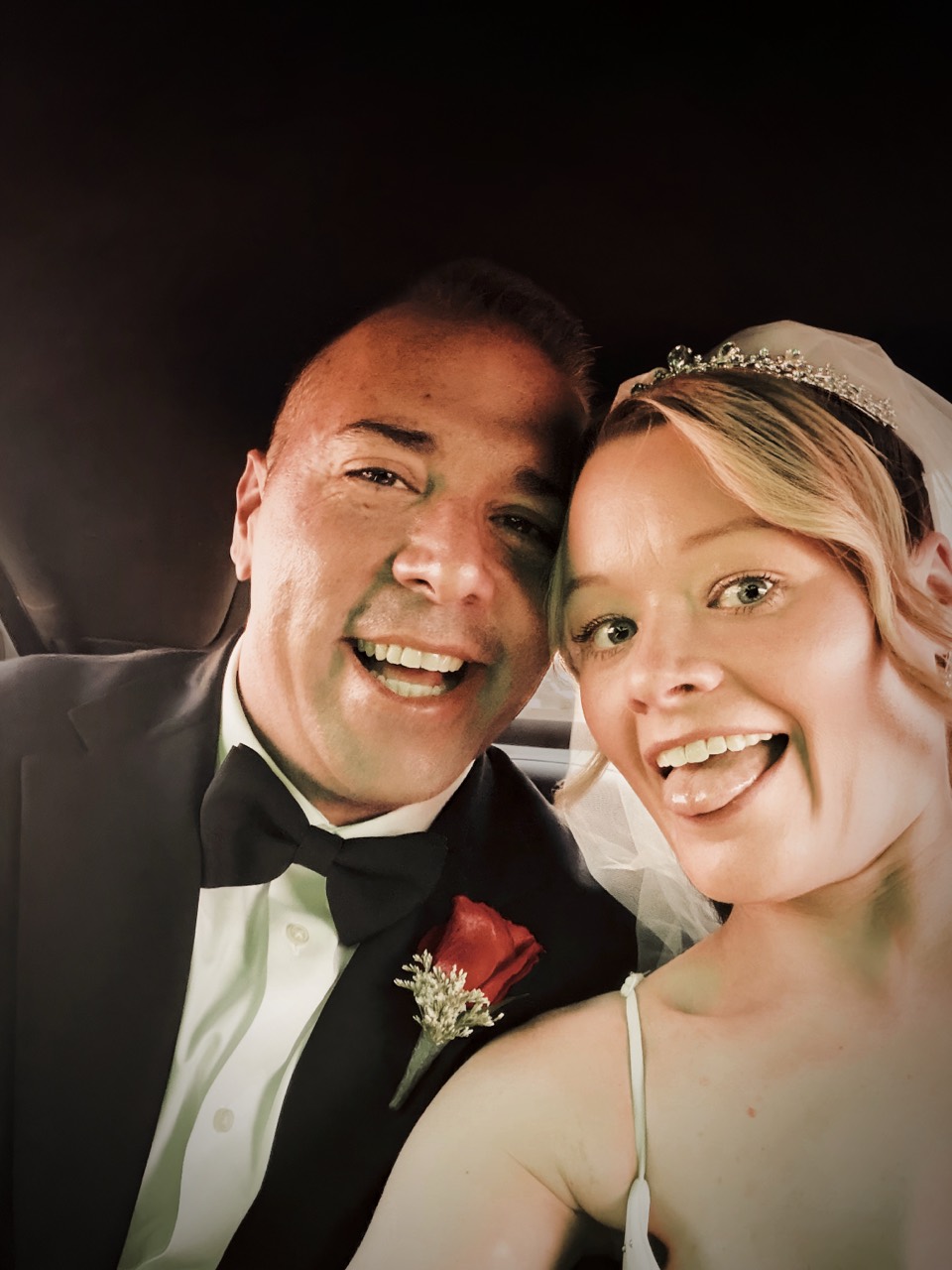 Jordan and Danielle laughing together in a car in wedding attire